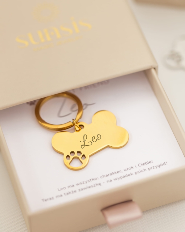 Złota adresówka dla psa w kształcie kości z grawerem w pudełku z dedykacją